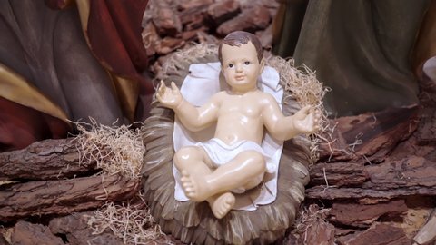Close-up of newborn Jesus Christ in manger with straw in stable, world savior birth installation. Christmas figurines decoration and ornaments. Jesus Christ Nativity scene, holy night concept