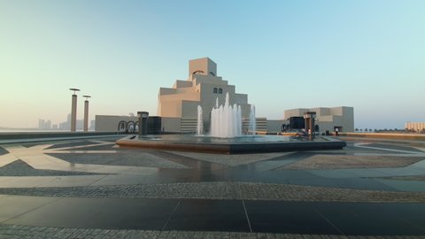 Doha, Qatar- September 25 2020 :Museum of Islamic Art exterior  walking in shot showing fountain in foreground and the main entrance to museum in background with car parking and people walking