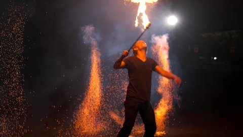 Two fire show artists spray fire sparks. The third man breathes fire. Impressive beautiful performance. Slow motion