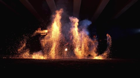 Fire show. An impressive performance by three artists. Two men spin fire sparks. The third man comes out of the fire and exhales a huge flame. Slow motion