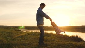 cheerful child plays with dad outdoors. daddy is spinning for the hands of happy child in the rays of the sunset in the park. little daughter plays with dad on beach in sun. happy family on vacation. - Powered by Shutterstock - Get 15% off with code: PIKWIZARD15