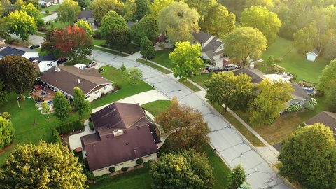 Aerial drone view of American suburban neighborhood. Establishing shot of America's  suburb, street. Residential single family houses, lush greenery. Autumn colors, Fall season, trees with yellow red 