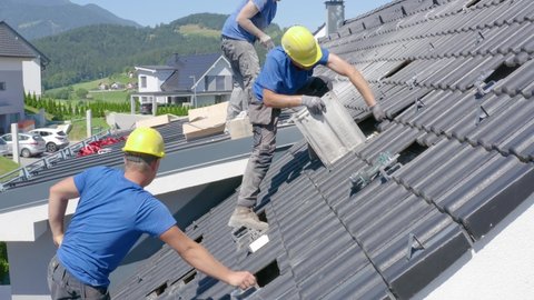 Men adjusting the tiles on the roof of a house for installation of solar panels. Concept of professionalism,Job,solar power,renewable energy. Side view.