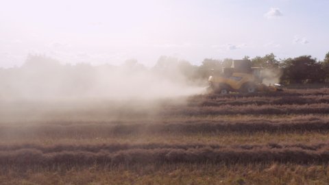 Drone Tracking Wide Shot Of Combine Harvester Harvesting Crops In Hazy, Sunlit Field