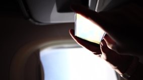 Adult man uses smartphone while traveling by plane