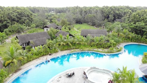 GAZIPUR, BANGLADESH - 27 SEPTEMBER 2020: Aerial 4K drone footage of a luxury five star resort in Bangladesh with a tropical swimming pool and bungalow villa's in the lush green forrest.