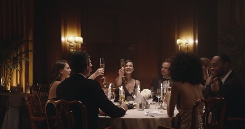 Group of men and women celebrating with wine at dinner party. Friends enjoying dinner at a gala night.
