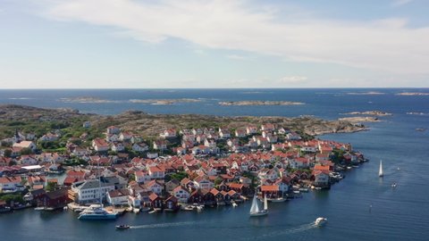 Swedish island homes and sailing boats in 4k drone shot. Aerial view over summer houses and flat granite stone islands in Sweden. Sunny view vacation atmosphere on west coast close to Gothenburg