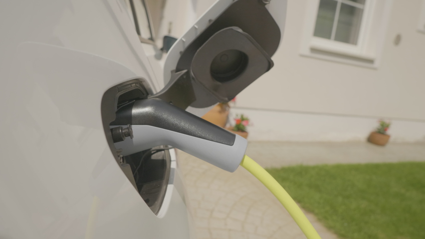 Woman's hands unplugging her electric automobile and closing the hatch in front of her home Royalty-Free Stock Footage #1059846218