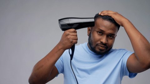 grooming, hairstyling and people concept - young african american man with fan or hair dryer over grey background