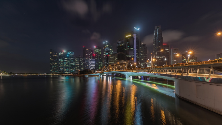 Esplanade bridge and downtown core skyscrapers in the background Singapore night to day transition timelapse. Illuminated towers reflected in water