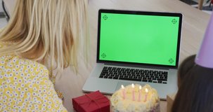 Caucasian woman spending time at home with her daughter together, girl blowing candles having video chat on laptop, slow motion. Social distancing during Covid 19 Coronavirus quarantine lockdown.
