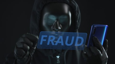 Hacker wearing black mask pulls FRAUD tab from a smartphone