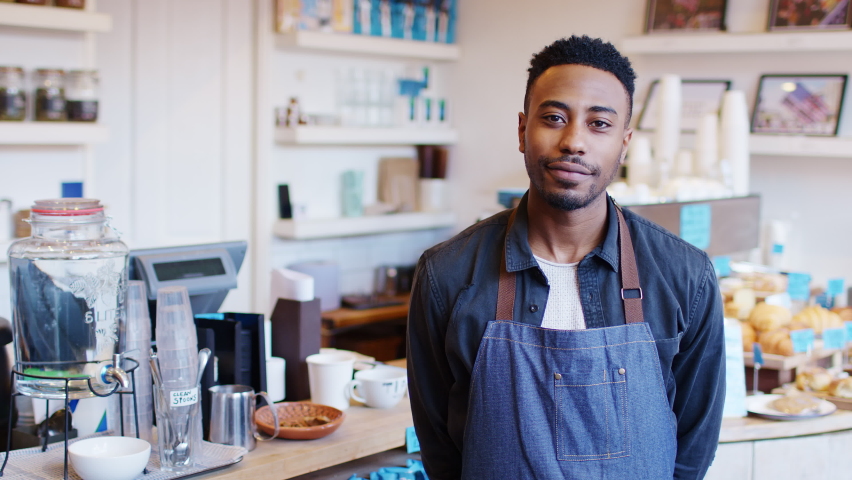Portrait of smiling man running local coffee shop standing behind counter - shot in slow motion Royalty-Free Stock Footage #1059851639
