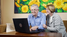 Happy husband and wife sitting in living room hugging and looking for something online. Attractive senior couple using laptop together at home. Grandma showing something to grandma on computer. - Powered by Shutterstock - Get 15% off with code: PIKWIZARD15