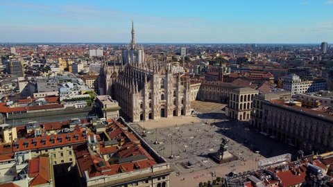 Aerial view of Piazza Duomo in front of the gothic cathedral in the center. Drone view of the gallery and rooftops during the day. Flight over the city. People in the city. Milan. Italy,