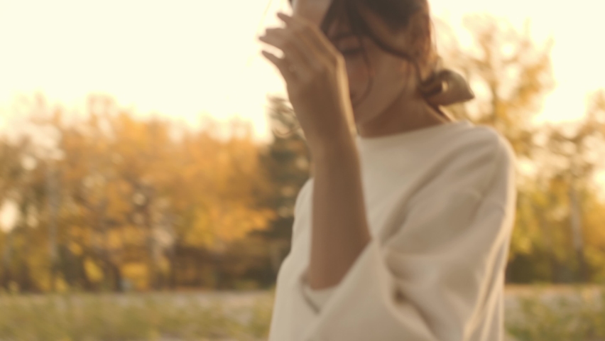 Portrait of an attractive brunette woman walking in the park at fall on a sunny day and smiling. The face of a happy beautiful woman in autumn outdoor. Slow-motion 4k footage