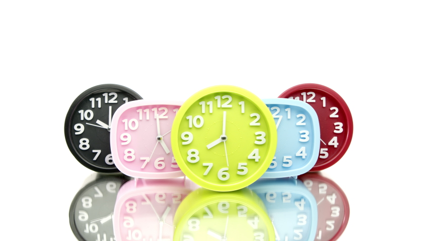 Colorful alarms ticking show different times, reflecting in glass table. different time zone concept. sleepyhead vs. early bird. time pass concept, deadline, simbol of unpunctuality.