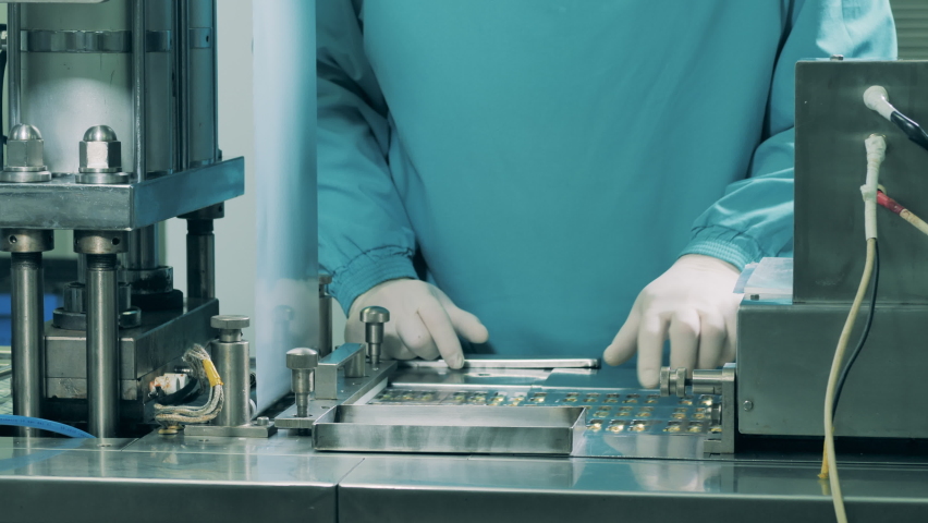 Production of medicines at a pharmaceutical production factory. Factory worker is managing a conveyor with capsule pills Royalty-Free Stock Footage #1059870383