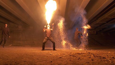 A lot of burning sparks fly in different directions. The man is breathing a huge flame. Fire escapes from the mouth. Performance of fire show artists in an abandoned place. Slow motion. 4K