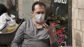 Man have couh in medical mask talking on a mobile phone using a modern messenger for video communication during a pandemic