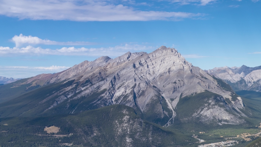 Town of Banff with surrounding mountains. Cascade Mountain, Lake Minnewanka and Mount Girouard in summer time season sunny day. Alberta, Canada. Time-lapse left to right 4K UHD. Royalty-Free Stock Footage #1059895397