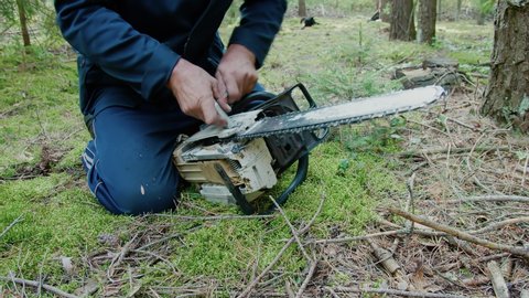 A forest worker prepares a chainsaw for work. Chainsaw chain tension. Chainsaw repair.