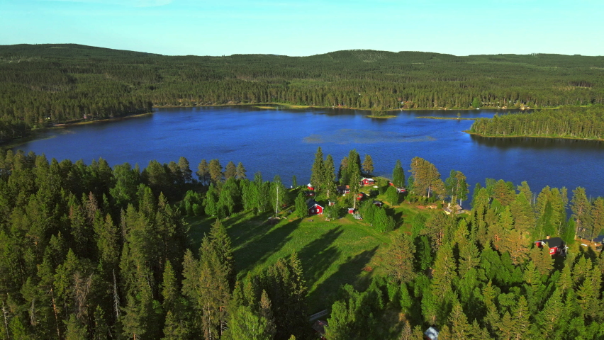 Picturesque Landscape Of Calm Lake By The Lush Green Forest With Camping Hotels And Picnic Area On A Sunny Summer Day In Vansbro, Dalarna County, Sweden. - aerial drone shot