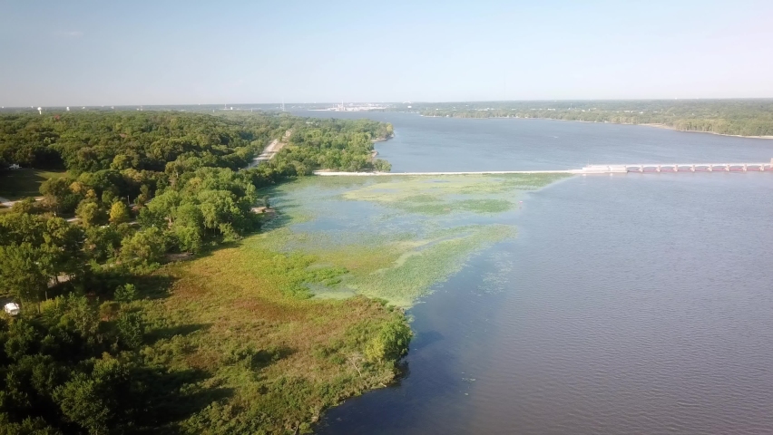 Aerial view of upstream backwater of Lock and Dam 14 on Mississippi River with dike, waterlilies, duckweed and trees along the shore