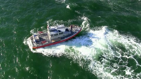 Ariel view of a US Coast Guard vessel initially reversing, thening forward along a travelled waterway.