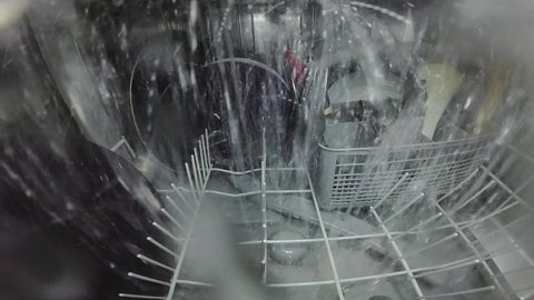 Slow motion. The master repairs the dishwasher and checks the operation of the nozzle mechanism, which rotates and sprays water. The process inside the dishwasher. Inside view of a dishwasher.