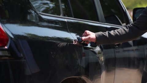 male hand opens the door of a black business class car. Silhouette of a woman in an elegant dress gets into a car