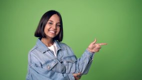 woman pointing finger to the side and presenting a product on green screen chroma key background