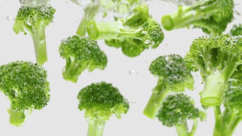 Pieces of Broccoli Falling Into Water, Isolated on White Background