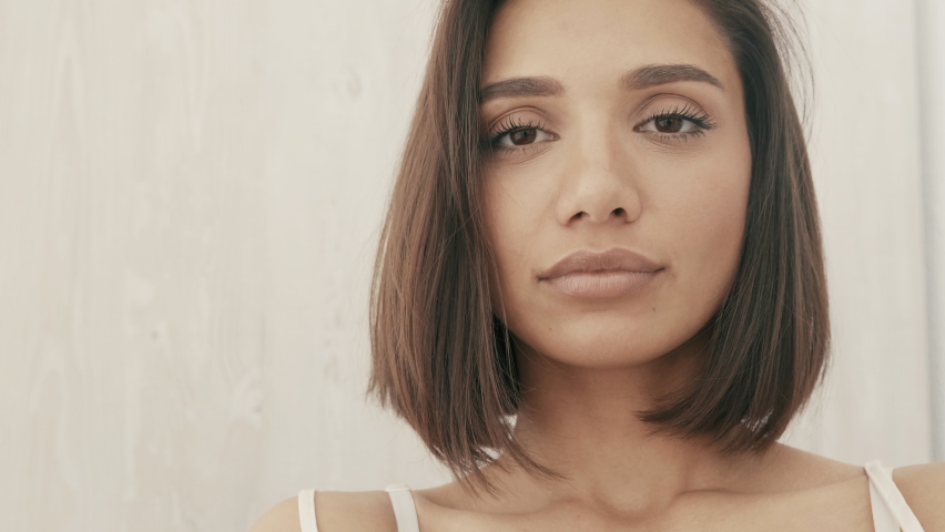 Closeup portrait of beautiful smiling woman dressed in white pajamas. Sexy carefree model enjoying her morning at balcony. She dreams about something and looking out at camera. Natural lips