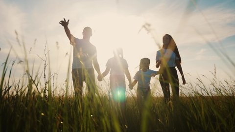 happy family walking together in the park silhouette. friendly family kid dream concept. lifestyle happy family walking holding hands in the park on the grass at sunset. friendly family dream together