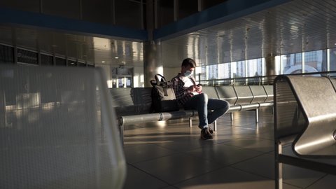 Waiting for flight at an empty airport. Man sitting on chair in empty airport lounge. Flights canceled. Problems with flights during quarantine. The collapse of airlines. Covid 19, coronavirus.