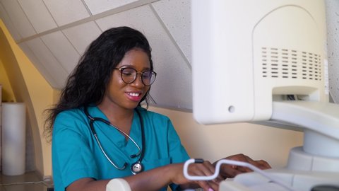 Happy professional african american obstetrician gynecologist performing ultrasound of belly of pregnant woman. Concept of medicine, health care and people