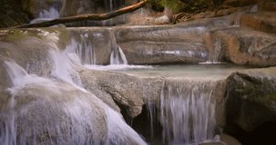 Close up tracking slider video shot of waterfall cascades in tropical rainforest of Thailand. Flowing fresh water