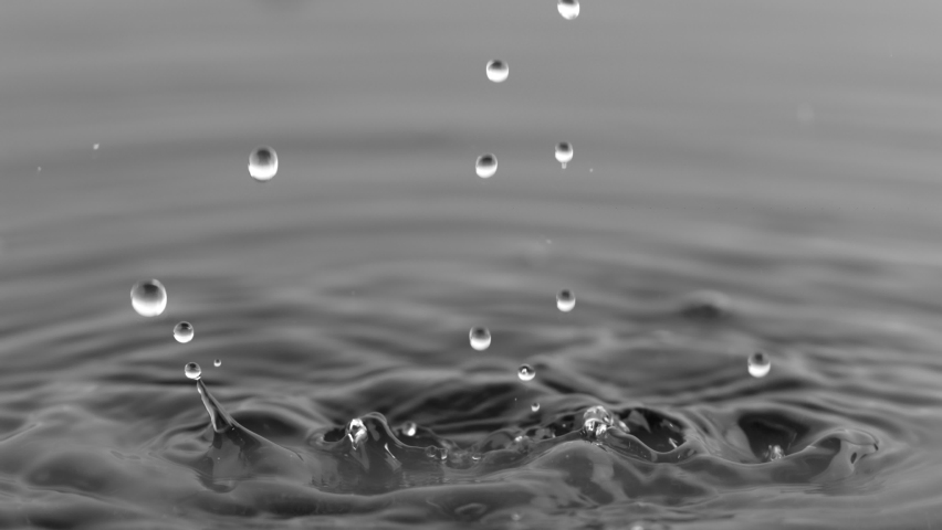 Super Slow Motion Shot of Water Drops Falling into Water on Black Background at 1000 fps. | Shutterstock HD Video #1059940022