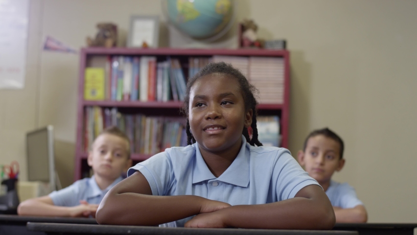 Primary students in uniforms sit in class as happy black girl raises her hand Royalty-Free Stock Footage #1059940112