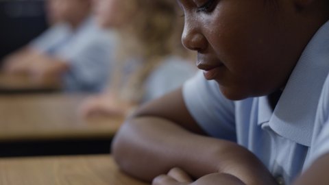 Young black girl looks up at the teacher and sighs. Student with depression.