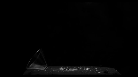 Top part of a martini glass shattering and spreading from the left side with a gun shot effect over a black background from the Fragment collection - Glass VFX Video Element.