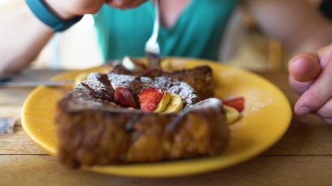 Slowmotion shot of a guy eating Frenchtoast in a Restaurant.