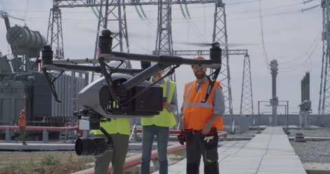 Men in waistcoats and hardhats launching modern drone while working on power station together