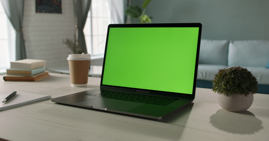 Modern laptop with mock up chroma key green screen st on desk of living room. The only template you need - remote work concept close up 4k video