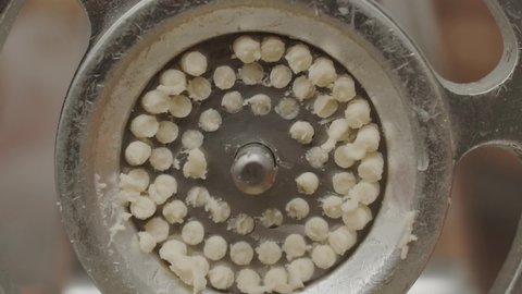 Closeup soft dough pressing through pasta maker during dish preparation in restaurant kitchen
