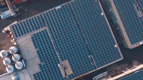 Rooftop of industrial building with solar cells on it. Photovoltaic solar panels on roof get clean energy from the sun. Slow motion. Aerial view.