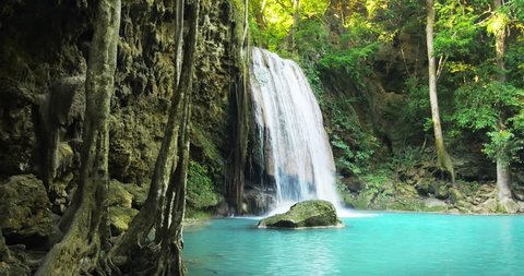 Tranquil and serene scene of waterfall falling in wild pond in jungle rainforest of Asia