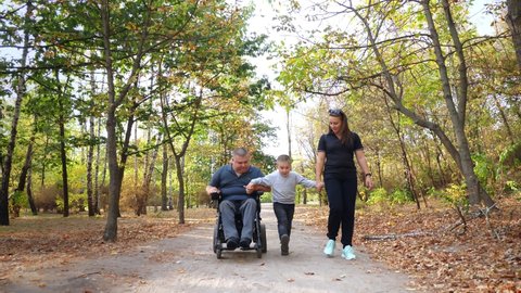 wheelchair man. Handicapped man. young disabled man in an automated wheelchair walks with his family, wife and small child, in the park, on sunny autumn day.